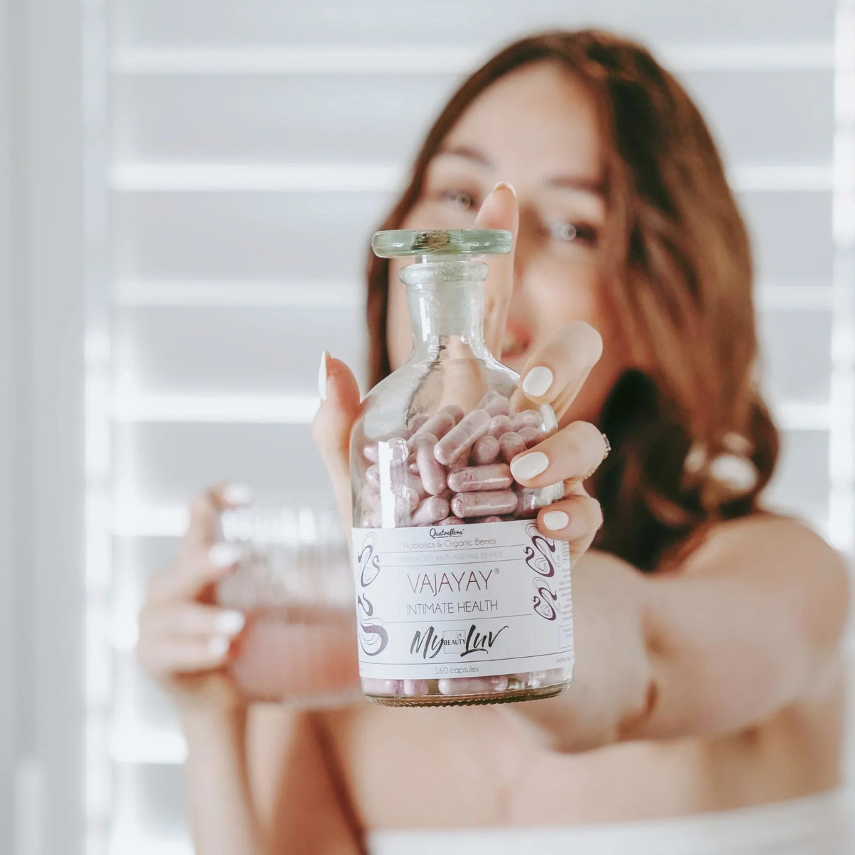 Woman holding a glass bottle with the label 'Vajayay'