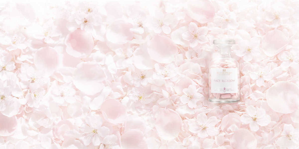 Supplement bottle named Face Blossom lying on a bed of soft pink rose and blossom petals