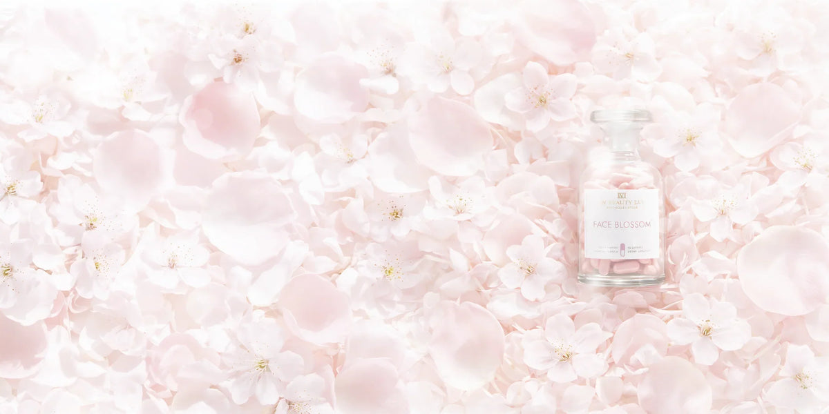 Supplement bottle named Face Blossom lying on a bed of soft pink rose and blossom petals