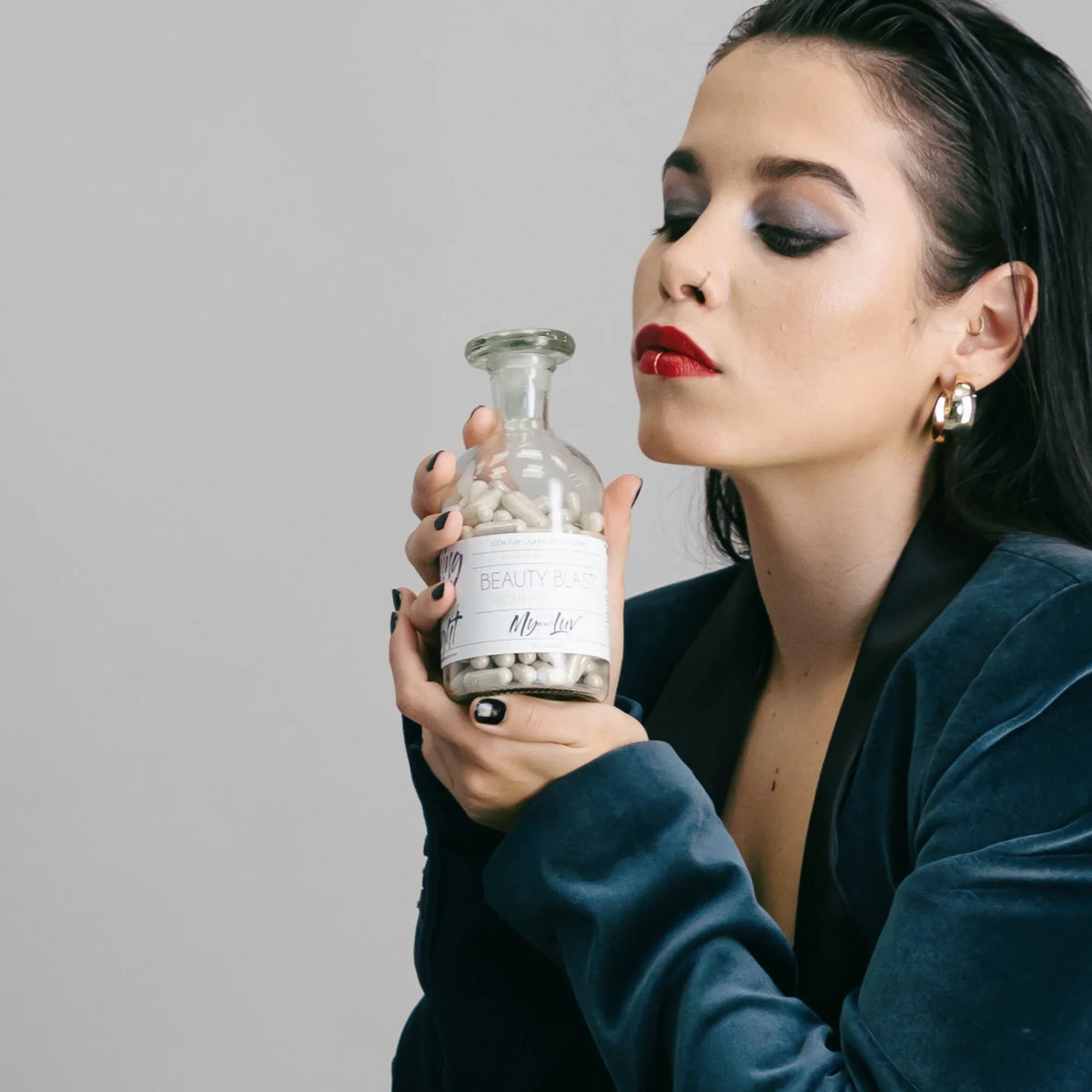 A woman hold up a glass bottle with the label Beauty Blast® by My Beauty Luv